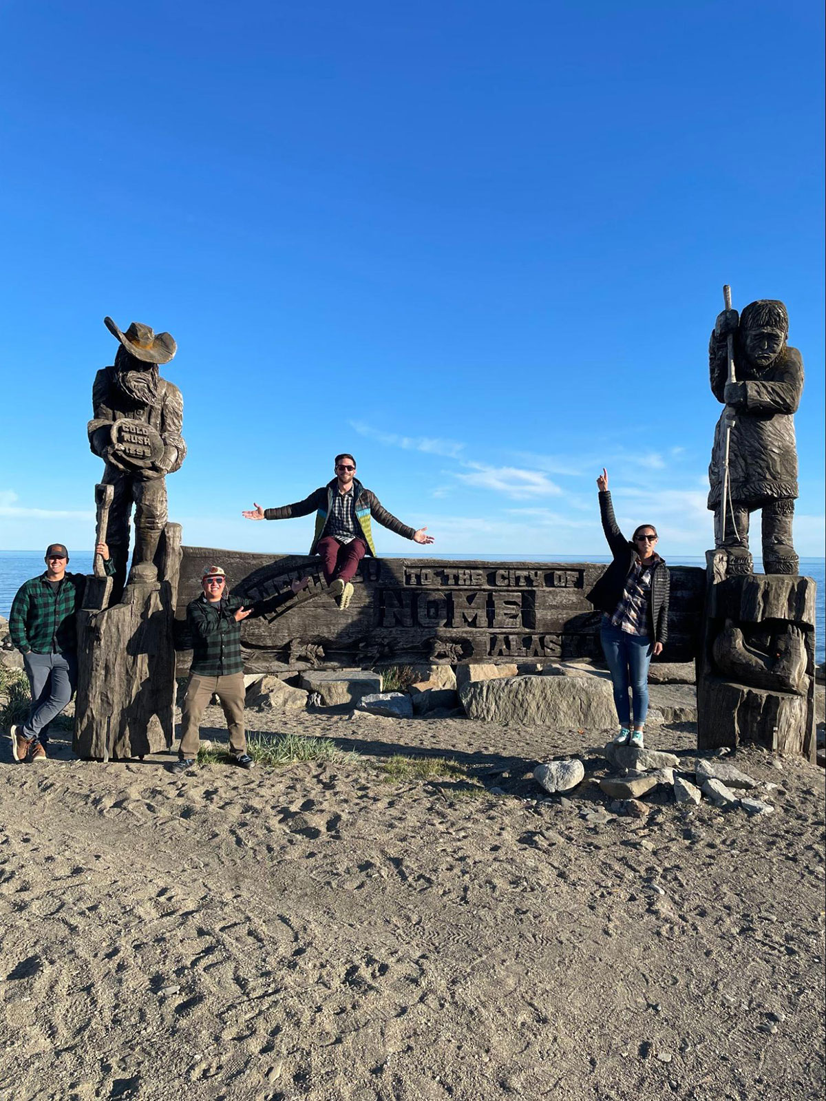 Adam Romlein and other members of the NOAA team posing at the Nome, AK welcome sign.